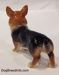 The back left side of a figurine that is of a black and tan Pembroke Welsh Corgi figurine. The figurine has large ears.