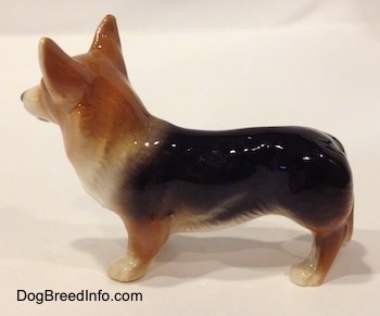 The right side of a black and tan Pembroke Welsh Corgie figurine. The figurine is glossy. The dog has a long body and shot legs.