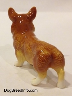 The back left side of a porcelain figurine that is of a brown with white Pembroke Welsh Corgi. The figurine has fine hair details.