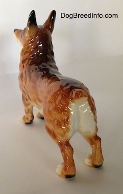 The back of a porcelain figurine that is a brown with white and black Pembroke Welsh Corgi. The figurine is glossy.