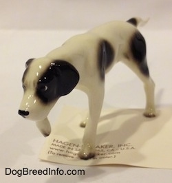 The front left side of a white with black Pointer in a pointing pose figurine. It is hard to differentiate the ears of the figurine from the head.