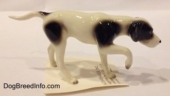 The right side of a white with black spotted Pointer in a pointing pose figurine.