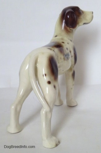 The back right side of a figurine of white and tan Pointer with brown patches. The figurines ears are hard to differentiate from the head.