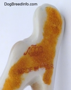 Close up - The underside of a porcelain Pointer figurine. There is orange felt on the bottom and on top of the felt is a red stamp that reds 'Made in the USSR'.