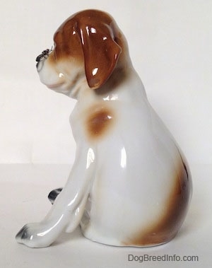 The left side of a Pointer puppy sitting with a fly on its nose figurine. The figurine has brown ears.