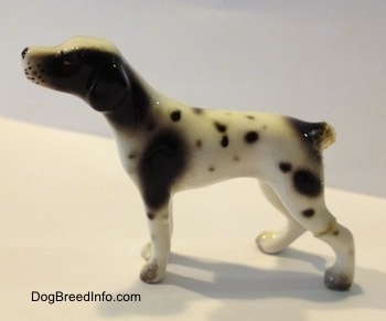 The left side of a white and black spotted figurine of a Pointer. The tail of the figurine is broken off.
