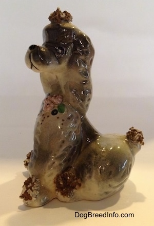The left side of a ceramic spaghetti Poodle figurine. The figurine has bristles at the top of its head and on its short tail.