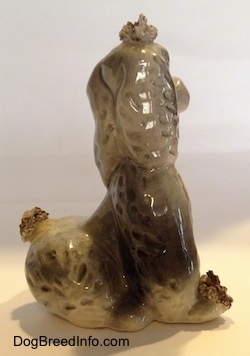 The right side of a ceramic spaghetti Poodle figurine. The figurine is grey and white.
