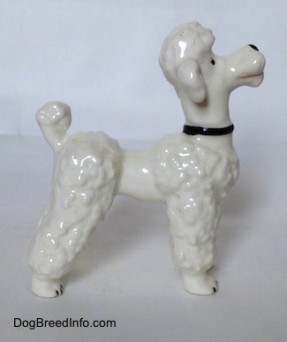 The right side of a figurine of a white Poodle that has hair poofs all along its long legs.