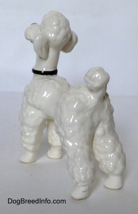 The back left side of a white Poodle figurine. The figurine has a hair poof on top of its head.