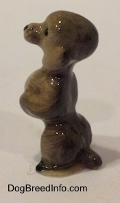 The left side of a miniature gray figurine of a Poodle in a begging pose. The ears of the figurine are hard to differentiate from the head.