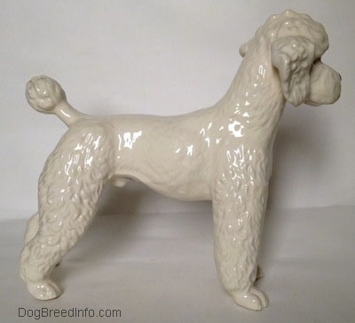 The right side of a white figurine of a Poodle. The figurine has stylized hair on top of its head.