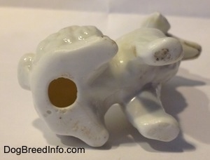 The underside of a white bone china Poodle figurine. The figurine has a hole on the bottom.