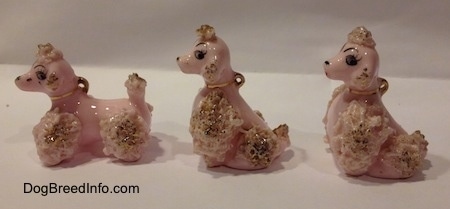 The left side of three porcelain pink spaghetti Poodle puppy figurines.