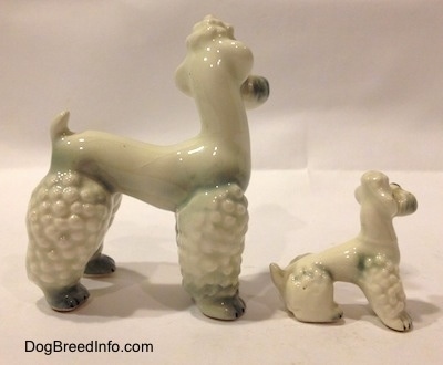 The right side of two white with spots of gray Poodle figurines. The figurines have hair poofs on there heads.