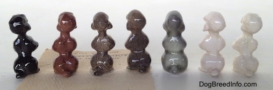 The back of a Poodle puppy figurine in a begging pose with seven different color variations. The figurines have short tails.