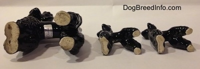 The underside of three black Poodle figurines.