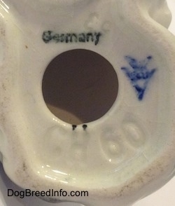 The bottom of a ceramic dog figurine with a the letter V and a bee inside the letter