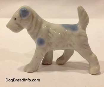 The left side of a Miniature Schnauzer figurine in a standing pose. The figurine has blue spot along it.