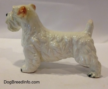 The left side of a white with brown Sealyham Terrier figurine. The figurine has fine hair details along its body.