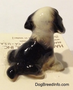 The back of a figurine of a black with white English Springer Spaniel figurine in a sitting position. The paws of the figurine are white.
