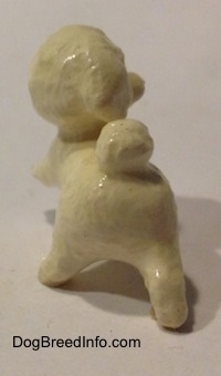 The back of a white with brown Toy Poodle walking figurine. The figurine has a hair poof for a tail.