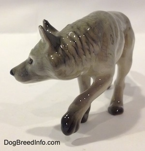 The front left side of a gray Wolf figurine stalking. The figurine has its ears in the air.