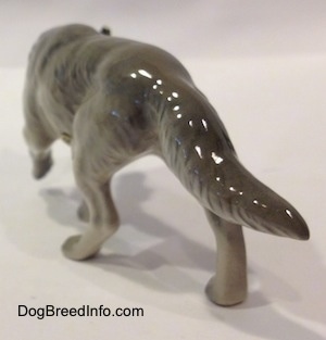 The back left side of a gray Wolf stalking figurine. The figurine has a long body.