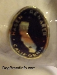 Close up - A gold and black sticker that is on the underside of a Wolf figurine.